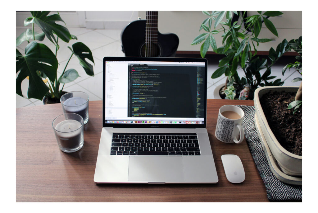 tepuedoayudar_ una mesa de oficia de un freelance que se acoge a la economía gig con un ordenador portátil, una taza de café y rato, con unas plantas a los lados